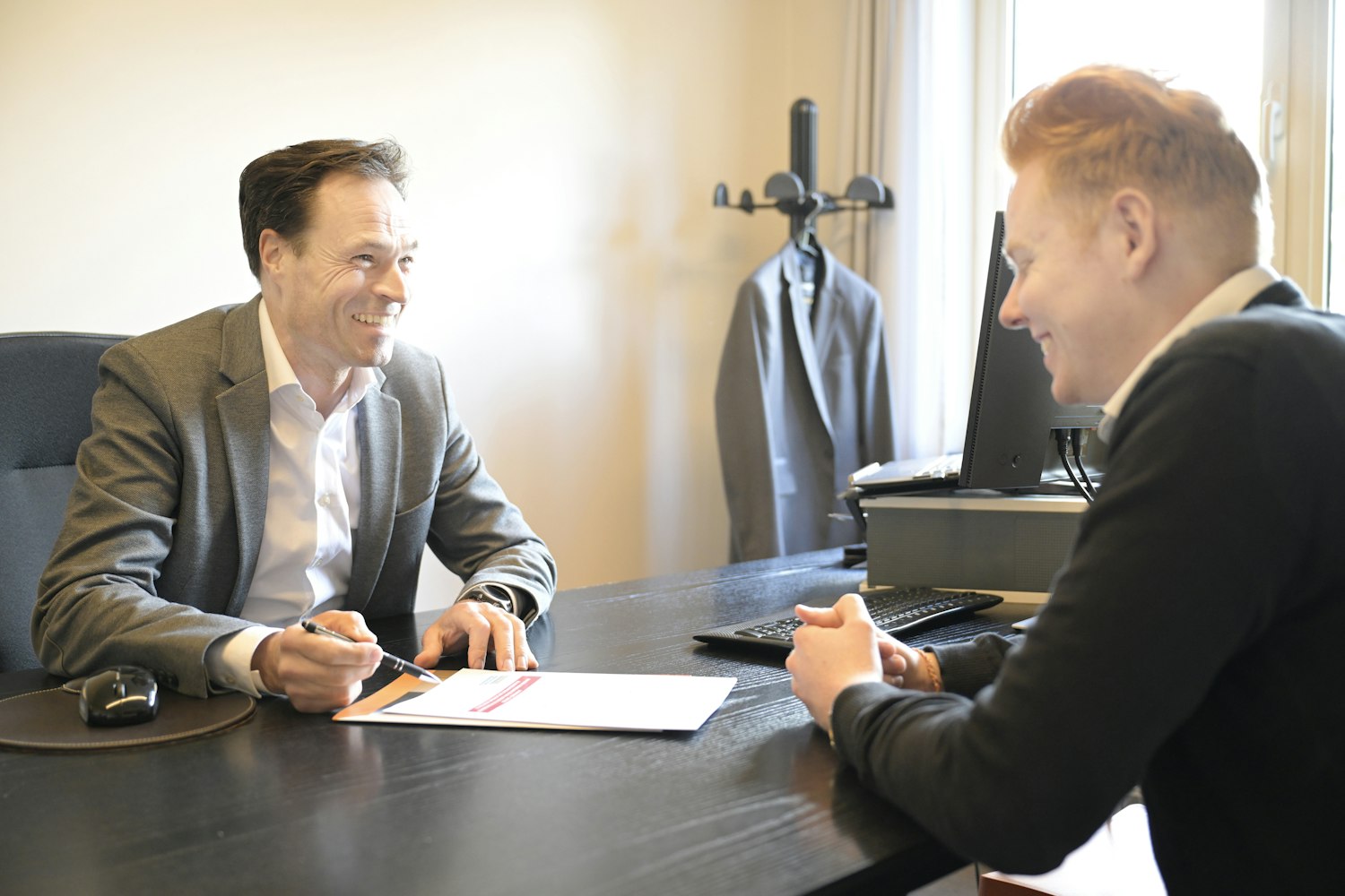 A structured interview: two people talking across a desk over a document